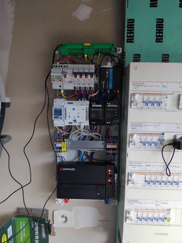 Panneau électrique avec plusieurs disjoncteurs et câblages visibles.